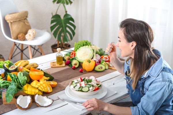 young-happy-woman-eating-salad-table_169016-1924